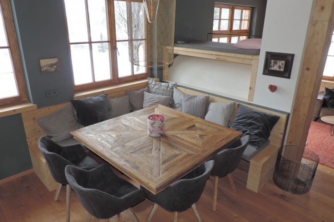 Esstisch mit grau gepolsterter Eckbank und Sesseln